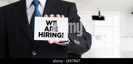 Geschäftsmann zeigt eine Visitenkarte mit der Nachricht, dass wir einstellen. Beschäftigungskonzept oder Einstellungskonzept Stockfoto