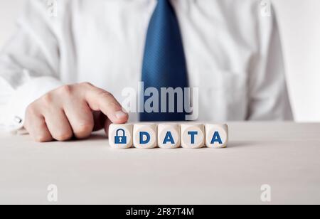Datensicherheitskonzept. Geschäftsmann drückt seinen Finger auf die Holzwürfel mit dem Wort Daten und einem Vorhängeschloss-Symbol. Stockfoto