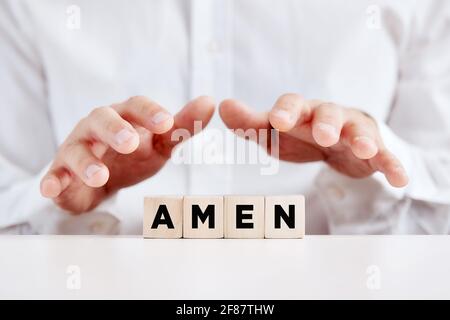 Der christliche Mann hält seine Hände mit dem Wort amen über die Holzwürfel. Stockfoto