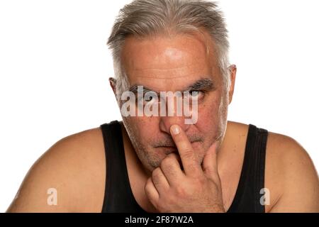 Besorgter Mann mittleren Alters berührt seine Nase auf weißem Hintergrund Stockfoto