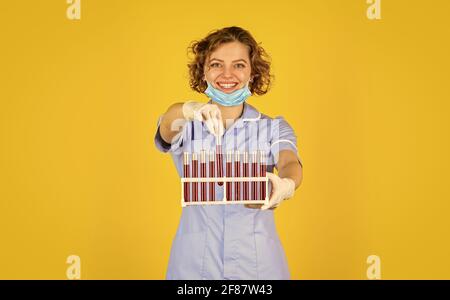 Laborforscherin. Frau trägt Schutzmaske. Laborexperiment. Testen Sie Ihr Blut. Wissenschaftler in Gesichtsmaske und Handschuhe halten Reagenzglas mit Stockfoto