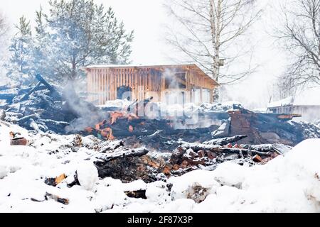 Ruinen des Hauses verbrannt im Feuer Feuerbrand auf Rauchschnee Winter Landschaft Hintergrund Stockfoto