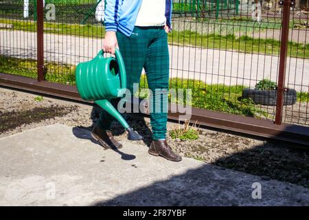 Der Gärtner mit Unschärfe-Effekt steht in der Nähe eines Bettes. Der Bauer bewässert die Betten. Grüne. Gartenbau und Landwirtschaft. Unscharfer Hintergrundboden. Wassertropfen. G Stockfoto