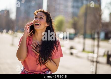 Glückliche junge Frau genießt sonnigen Tag im Freien in der Stadt. Stockfoto
