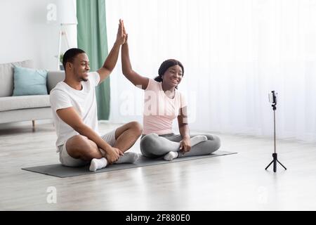 Fröhliches schwarzes Paar zusammen trainieren, mit Online-Klasse Stockfoto