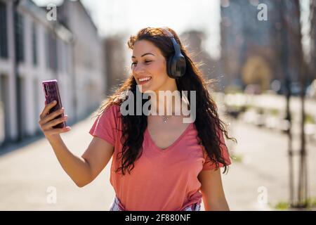 Glückliche junge Frau genießt sonnigen Tag im Freien in der Stadt. Stockfoto