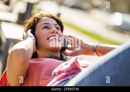 Glückliche junge Frau genießt sonnigen Tag im Freien in der Stadt. Stockfoto