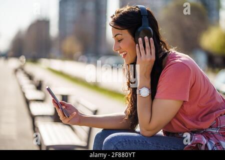 Glückliche junge Frau genießt sonnigen Tag im Freien in der Stadt. Stockfoto