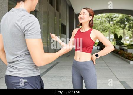Ziemlich lächelnd junge asiatische Sportlerin im Gespräch mit Freund vor dem Joggen Im Freien Stockfoto
