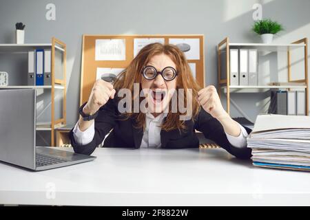 Emotionaler, verrückter Buchhalter, der am Schreibtisch sitzend Fäuste schrie. Stockfoto