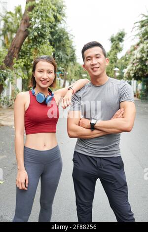 Porträt eines lächelnden, selbstbewussten jungen asiatischen Paares, das darauf steht Straße und Blick auf die Kamera nach dem Training Stockfoto