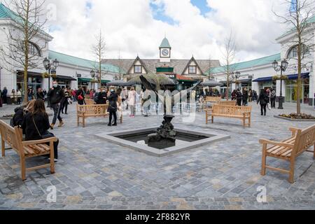 CANNOCK, STAFFORDSHIRE, GROSSBRITANNIEN. April 2021. Nicht unbedingt erforderliche Geschäfte dürfen heute ihre Türen für Käufer öffnen. Der Designer Outlet-Einkaufskomplex in Cannock, Staffordshire, öffnete heute zum ersten Mal seine Türen, nachdem er kürzlich fertiggestellt wurde. Am Brunnen auf dem hauptplatz versammeln sich Menschen. Kredit: Richard Grange/Alamy Live Nachrichten Stockfoto