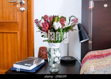 Schöner Blumenstrauß in einer Vase auf einem Nachttisch. Stockfoto