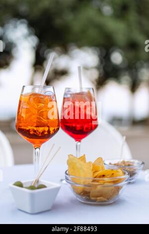 Zwei erfrischende italienische Cocktails mit Snacks auf dem Tisch (Vertikales Foto) Stockfoto