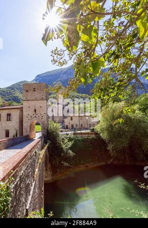 Ansicht der römisch-katholischen Abtei (San Vittore alle Chiuse) von der mittelalterlichen Brücke. Genga, Marken, Italien (Vertikales Foto) Stockfoto