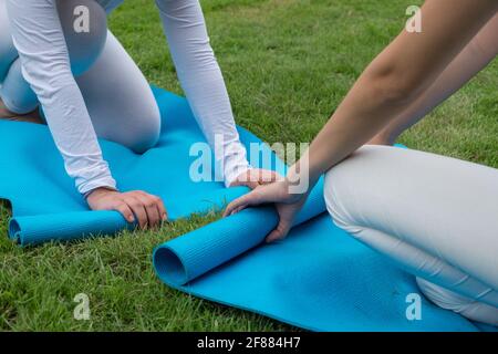 2 Frauen halten nach dem Yoga-Kurs eine Yogamatte. Stockfoto