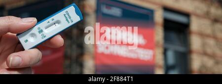 Express COVID-19-Test vor der Werbung für schnelle Coronavirus-Tests in Berlin. Panoramabild, Bannerdesign. Schnelltest auf Deutsch Stockfoto