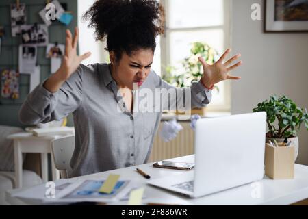 Frustrierte junge Frau mit Laptop drinnen zu Hause, Home-Office-Konzept. Stockfoto