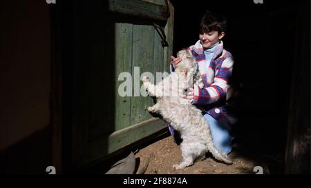 Armes kleines Mädchen spielt mit Hund im Freien vor dem Haus, Armut Konzept. Stockfoto