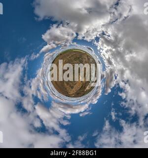 Winziger Planet in blauem Himmel mit schönen Wolken. Transformation des sphärischen Panoramas 360 Grad. Sphärische, abstrakte Luftaufnahme. Raumung. Stockfoto