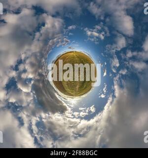 Winziger Planet in blauem Himmel mit schönen Wolken. Transformation des sphärischen Panoramas 360 Grad. Sphärische, abstrakte Luftaufnahme. Raumung. Stockfoto