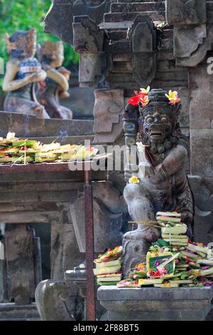 Traditionelle Steinstatue am Tempel mit Blumenopfern und Weihrauch in Bali, Indonesien Stockfoto