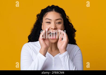 Junge Afroamerikanische Frau, Die Laut Vor Die Kamera Schreit Und Eine Ankündigung Macht Stockfoto