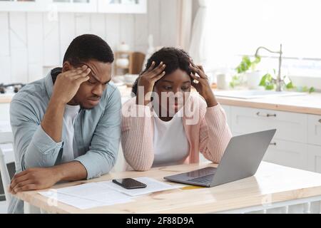 Konzept Der Finanzkrise. Verärgert Schwarz Ehegatten Blick Auf Elektronische Rechnungen In Laptop Stockfoto