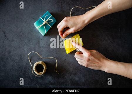 Frau Hände Verpackung Bio handgemachte Seifenstücke. Draufsicht. Dunkler Hintergrund Stockfoto