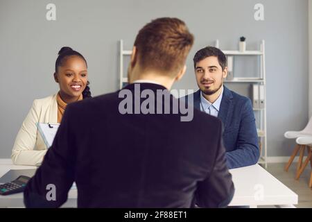 Glückliches junges Paar im Gespräch mit dem Bankmanager, Versicherungsberater oder Hypothekenmakler Stockfoto