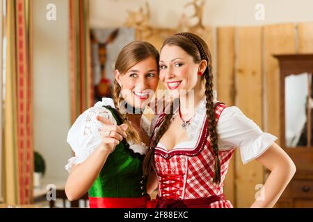 Junge Menschen - zwei Frauen - in traditionelle bayerische Tracht im Restaurant oder im Pub Stockfoto