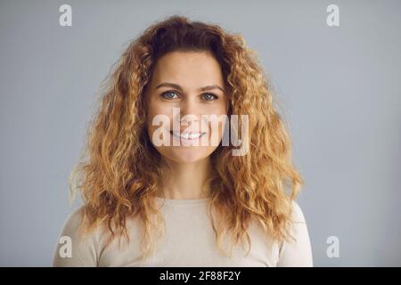 Studio-Kopfaufnahme einer glücklichen Frau mit langen Wellen Haare und ein freundliches weißes Lächeln Stockfoto