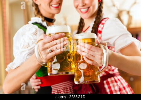 Zwei junge Frauen in traditionellen bayerischen Tracht im Restaurant oder Pub mit Bier und Bierkrug Stockfoto