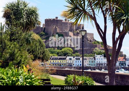 Jersey, Großbritannien - 09. Juni 2011: Mont Orgueil Castle aka Gorey Castle mit Jachthafen und Gebäuden in der winzigen Stadt Gorey, exotische Pflanzen wachsen in t Stockfoto