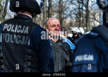Warschau, 10. April 2021: Anti-Aufstands-Polizisten sprechen während des Protestes gegen die Regierung mit einem verletzten Demonstranten, während Polen an das Smolensk-Flugzeug erinnert Stockfoto