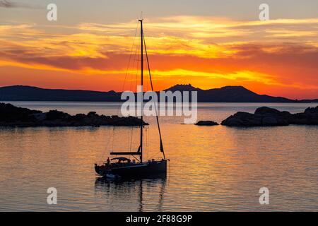 Genießen Sie einen goldenen Sonnenuntergang: Die Yacht liegt an ruhigen Gewässern Sardiniens, über ein ruhiges Mittelmeer zu den Inseln La Madallena und Caprera Stockfoto