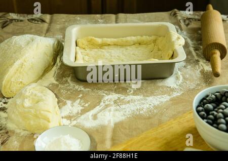 Mamas Kuchen. Der Teig wird in eine Backform gegeben. Sie können die Füllung verteilen. Kochen während der Quarantäne. Stockfoto