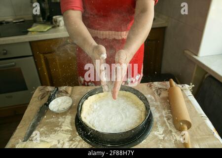 Mamas Kuchen. Der Teig wird in eine Backform gegeben. Vor dem Ablegen der Füllung bestreut MUM den Teig mit Stärke. Kochen während der Quarantäne. Stockfoto