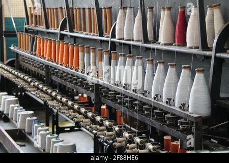 Fäden und Spulen auf einer klassischen Textilmaschine. Stockfoto