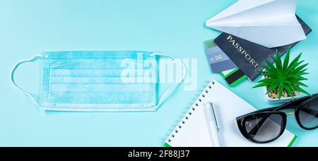 Reisepass und medizinische Maske auf blauem Hintergrund. Sicheres Reisekonzept während der Coronavirus-Pandemie. Flatlay, Kopierbereich. Stockfoto