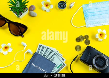 Reisepass, medizinische Maske und Sonnenbrille auf gelbem Hintergrund. Sicheres Reisekonzept während der Coronavirus-Pandemie. Flatlay, Kopierbereich. Stockfoto