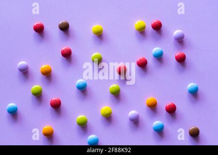 Bunte Schokolade Süßigkeiten Smarties auf lila Hintergrund. Stockfoto