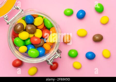 Bunte Schokolade Bonbons im Glas auf rosa Hintergrund.Draufsicht bunte Süßigkeiten Hintergrund Konzept. Stockfoto