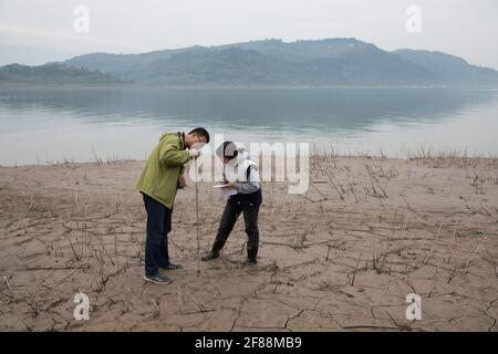 (210412) -- ZHONGXIAN, 12. April 2021 (Xinhua) -- Forscher überwachen den Bodenzustand in der Fluktuationszone des drei-Schluchten-Stausees im Bezirk Zhongxian, Chongqing, im Südwesten Chinas, 10. April 2021. Das drei-Schluchten-Projekt ist ein riesiges, multifunktionales Wasserkontrollsystem am Jangtze-Fluss, Chinas längster Wasserstraße, mit einem 2,309 Meter langen und 185 Meter hohen Staudamm.der Wasserstand des Stausees schwankt unweigerlich bei einem jährlichen Abfluss-Speicherzyklus zwischen 145 und 175 m am Staudamm. Die Wasserpegelschwankungszone stößt auch auf einige Öko-Umweltprobleme, einschließlich Stockfoto