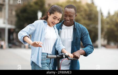 Schwarzer Kerl und Frau mit Fahrt auf Elektro-Kick Scooter Stockfoto