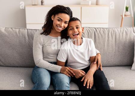 Porträt von schwarzer Mutter und Sohn umarmt auf der Couch Stockfoto