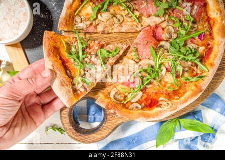 Leckere traditionelle italienische Pizza mit Schinken und Pilzen, auf weißem Holzhintergrund. Mediterranes Rezepturkonzept, Draufsicht Stockfoto