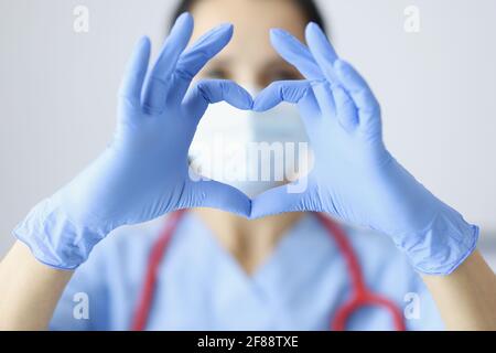 Arzt in Gummihandschuhen, die das Herz mit den Händen in Nahaufnahme zeigen Stockfoto