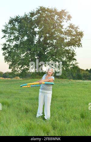 Ältere Frau mit Hula Hoop Reifen im Park Stockfoto