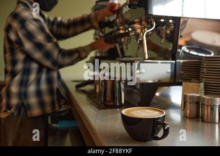 Nahaufnahme der Kaffeetasse an der Theke im Café oder Café mit unerkennbarem Barista im Hintergrund, Kopierbereich Stockfoto
